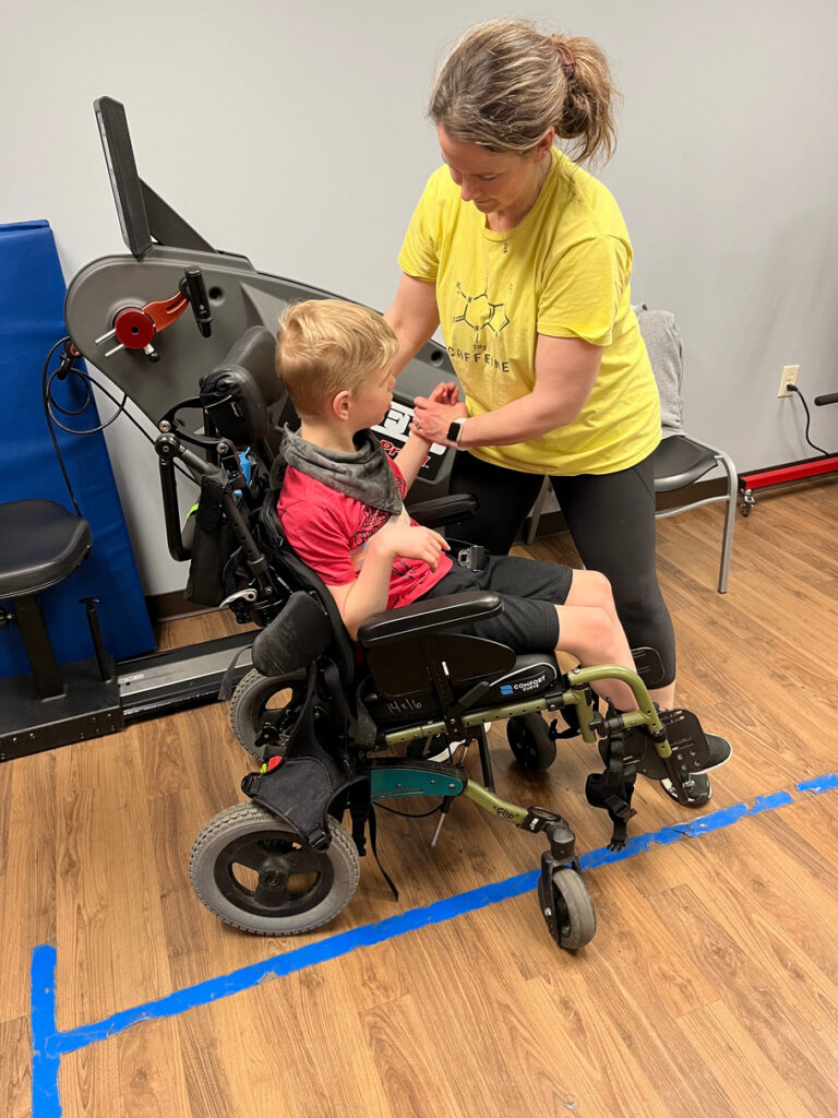 Caregiver preparing to lift young boy out of his wheelchair.